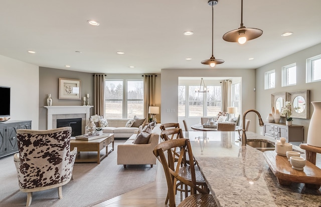 living room with a notable chandelier, a fireplace, sink, and a wealth of natural light