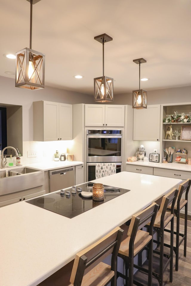 kitchen featuring dishwasher, a breakfast bar area, black electric cooktop, double oven, and a sink