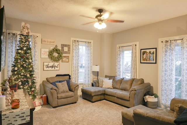 carpeted living area with a textured ceiling and a ceiling fan