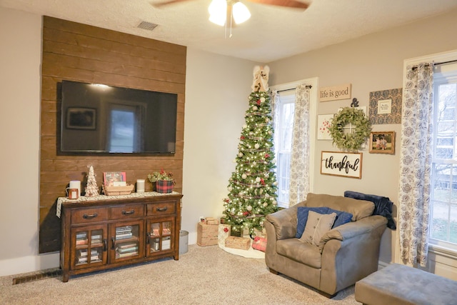 living area featuring carpet flooring, visible vents, and a healthy amount of sunlight