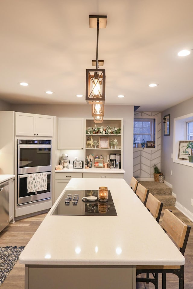 kitchen with light wood-style flooring, a breakfast bar, a center island, stainless steel appliances, and white cabinetry