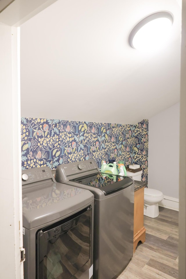 clothes washing area featuring washing machine and clothes dryer, light wood-style floors, laundry area, baseboards, and wallpapered walls