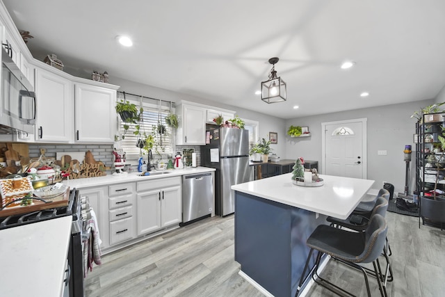 kitchen with white cabinetry, pendant lighting, a kitchen island, and stainless steel appliances