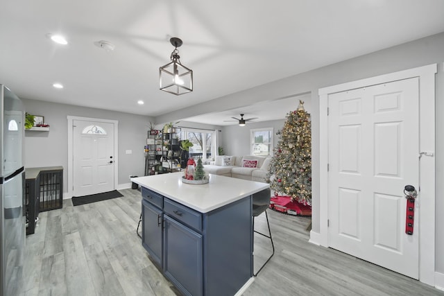 kitchen featuring ceiling fan, a kitchen island, decorative light fixtures, light hardwood / wood-style floors, and a breakfast bar area