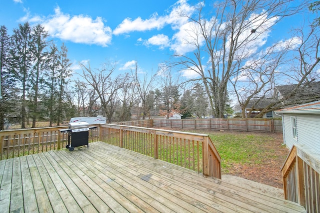 wooden deck featuring a lawn and a grill