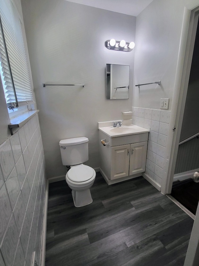 bathroom featuring vanity, wood-type flooring, tile walls, and toilet