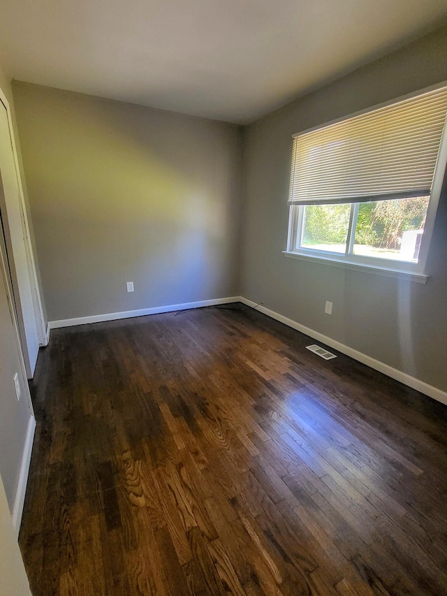 unfurnished room with dark wood-type flooring