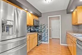 kitchen with sink, light wood-type flooring, stainless steel appliances, and light brown cabinetry