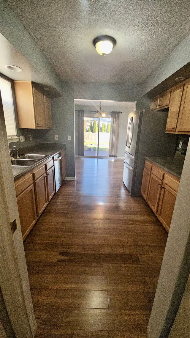 kitchen with stainless steel dishwasher, a textured ceiling, sink, and dark wood-type flooring