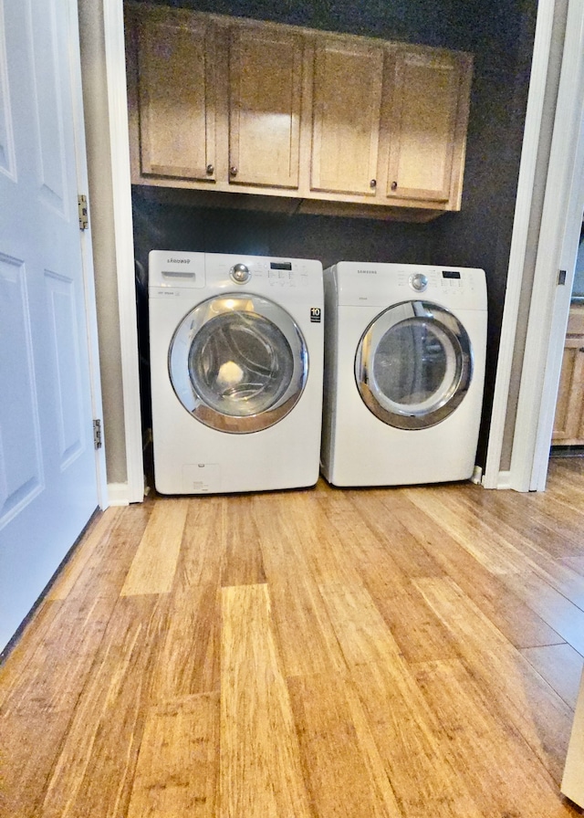 washroom featuring washer and dryer, cabinets, and light hardwood / wood-style flooring