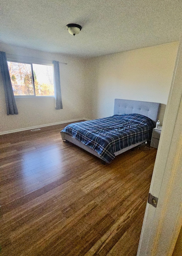 bedroom with a textured ceiling and dark hardwood / wood-style floors