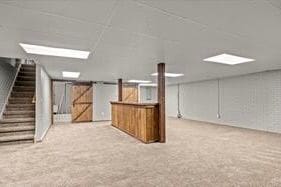 basement featuring a barn door and light carpet