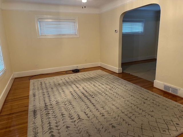 empty room with wood-type flooring, plenty of natural light, and ornamental molding