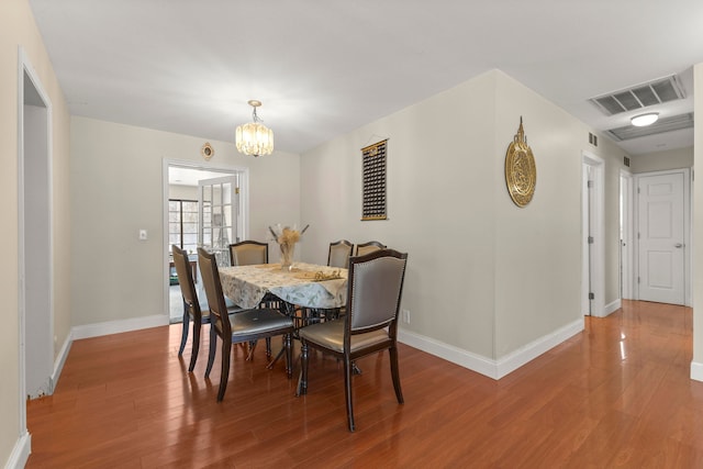 dining area featuring wood-type flooring and an inviting chandelier