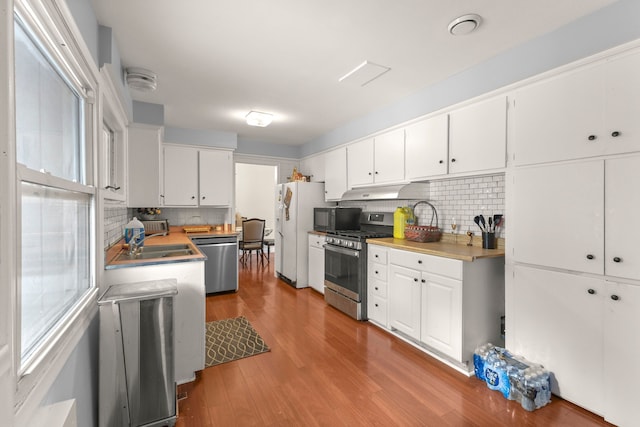 kitchen featuring decorative backsplash, stainless steel appliances, sink, white cabinets, and light hardwood / wood-style floors