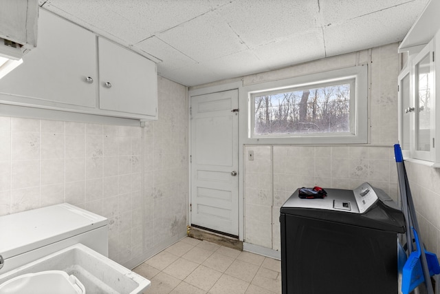 bathroom featuring a drop ceiling, washer and dryer, and tile walls