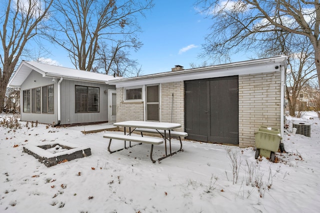 snow covered property with central AC and an outdoor fire pit