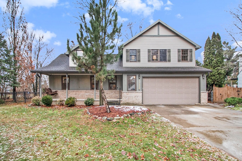 view of front of property with a porch, a front yard, and a garage