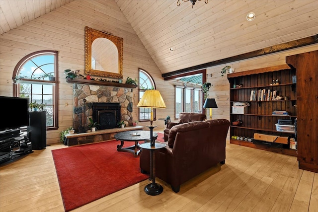 living room featuring high vaulted ceiling, a fireplace, wood walls, and light hardwood / wood-style floors