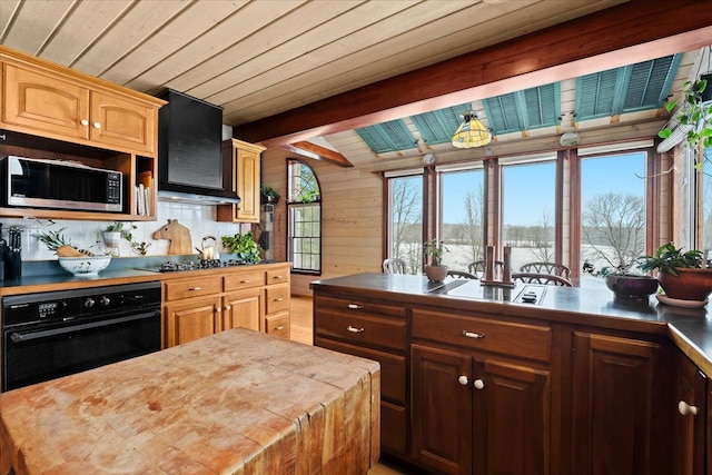 kitchen with wooden counters, black oven, wooden ceiling, wall chimney exhaust hood, and beam ceiling