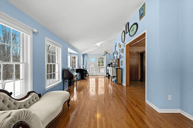 hallway with wood-type flooring, lofted ceiling, and french doors