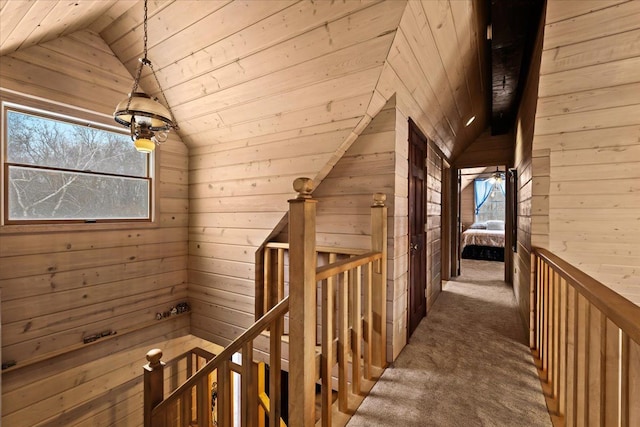 hallway with wooden ceiling, dark carpet, lofted ceiling, and wooden walls