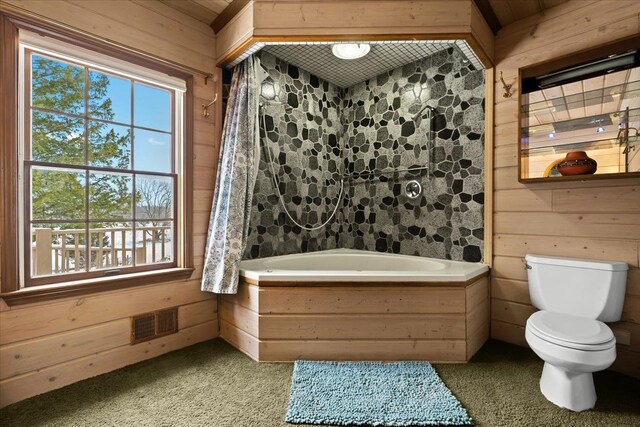 bathroom with a bath, toilet, and wooden walls