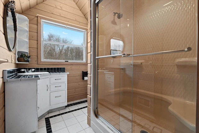 bathroom with tile patterned floors, a shower with door, vanity, and wooden walls