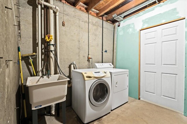 clothes washing area with washing machine and dryer and sink