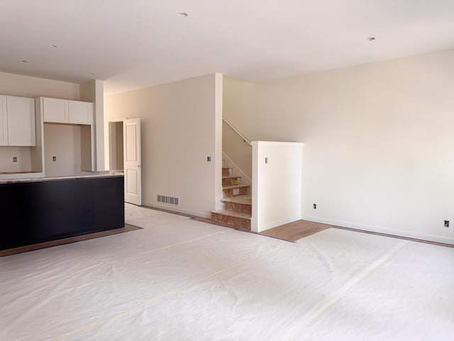 unfurnished living room with stairs, baseboards, and visible vents