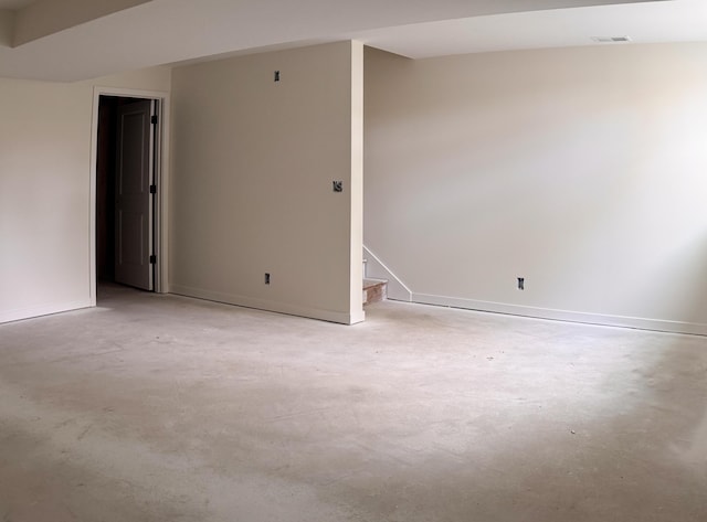 spare room with unfinished concrete floors, stairs, baseboards, and visible vents