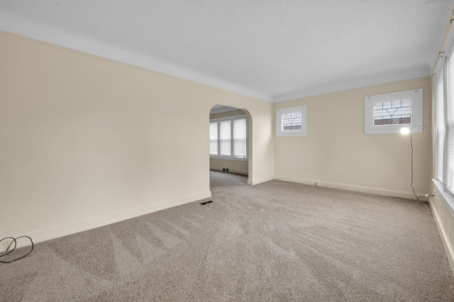 unfurnished room with a textured ceiling and light colored carpet