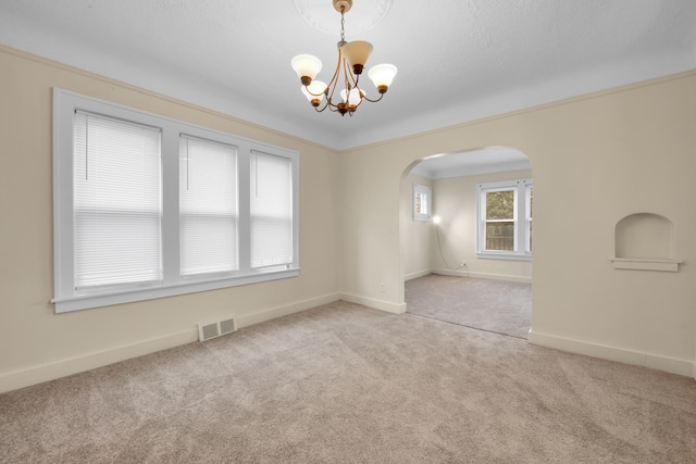 unfurnished room featuring light carpet, crown molding, and an inviting chandelier