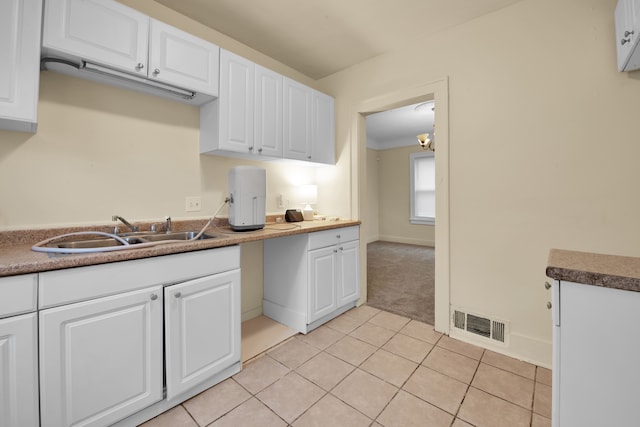 kitchen featuring light tile patterned flooring, white cabinetry, and sink