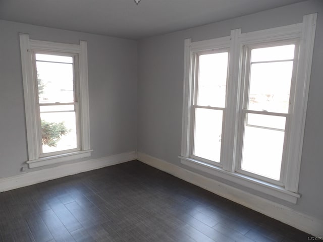 spare room with dark hardwood / wood-style floors and plenty of natural light