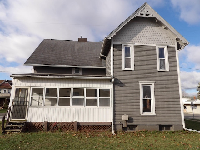 back of property with a yard and a sunroom