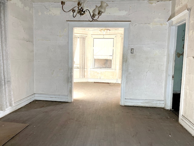 spare room featuring dark wood-type flooring and a notable chandelier