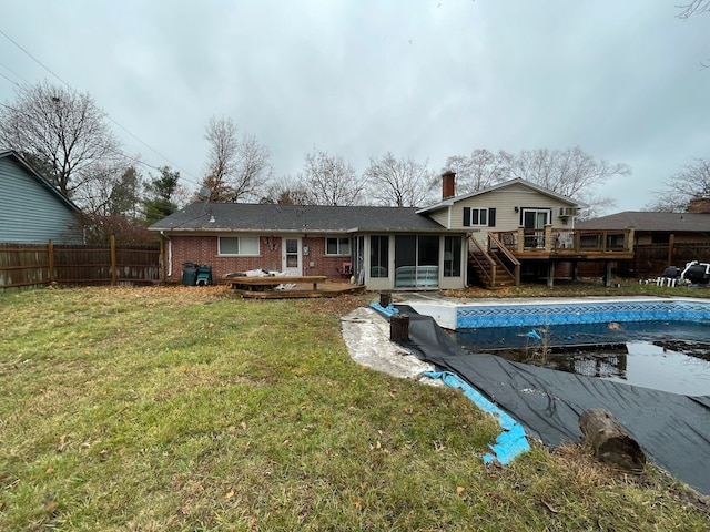 back of property featuring a yard, a pool side deck, and a sunroom