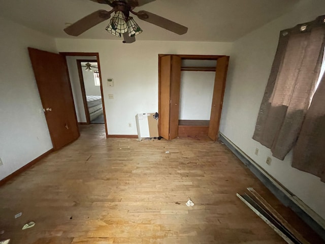 unfurnished bedroom with ceiling fan, a closet, radiator, and light hardwood / wood-style flooring