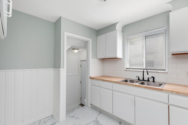 kitchen with backsplash, white cabinetry, sink, and wooden counters