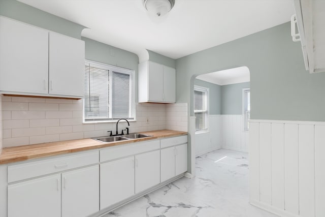 kitchen with decorative backsplash, butcher block counters, white cabinetry, and sink