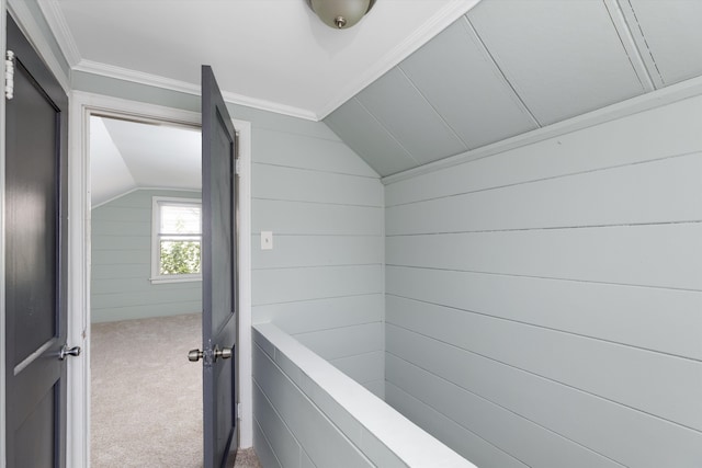hall with carpet flooring, wood walls, and lofted ceiling