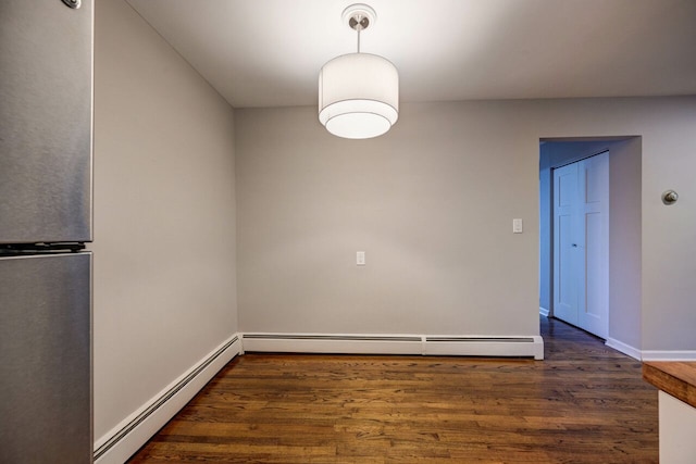 spare room with dark hardwood / wood-style flooring and a baseboard heating unit