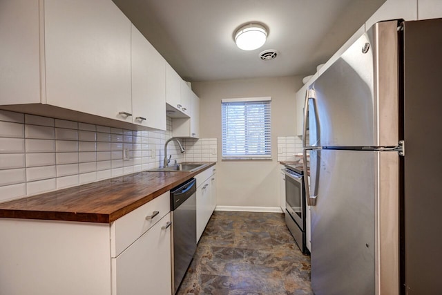 kitchen featuring wood counters, appliances with stainless steel finishes, decorative backsplash, sink, and white cabinetry