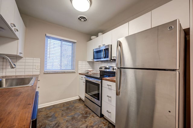 kitchen with butcher block counters, sink, white cabinets, and stainless steel appliances