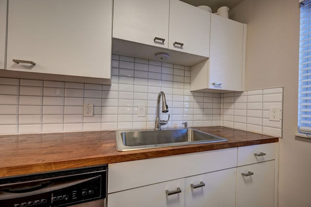 kitchen featuring white cabinetry, sink, stainless steel dishwasher, wooden counters, and backsplash