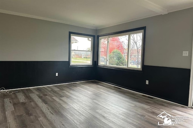 spare room with crown molding, beamed ceiling, and wood-type flooring