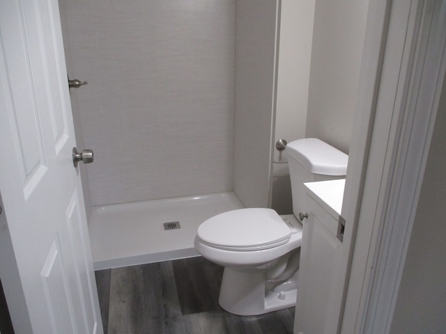 bathroom featuring a shower, wood-type flooring, vanity, and toilet