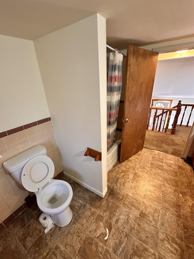 bathroom with shower / tub combo, toilet, and tile walls