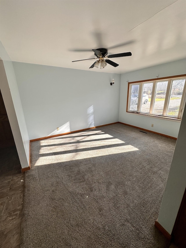 spare room featuring dark colored carpet and ceiling fan